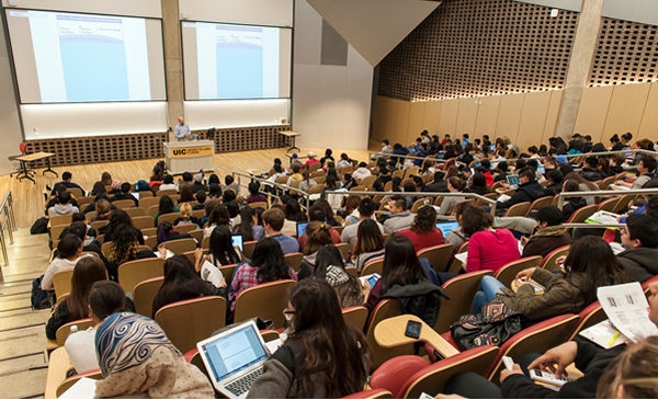 Lecture style classroom, students seated in rows facing an instructor at a podium